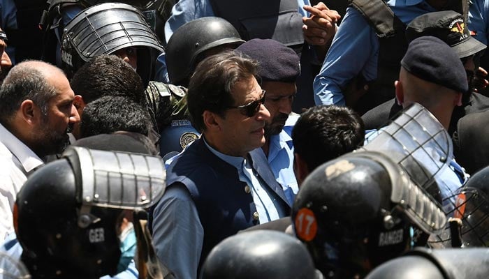 Police commandos escort former prime minister Imran Khan (C) as he arrives at the high court in Islamabad on May 12, 2023. — AFP