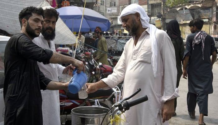 Volunteers distribute free lemon water to passersby following hot weather at Bohar Bazaar in Rawalpindi on June 23, 2023. — Online