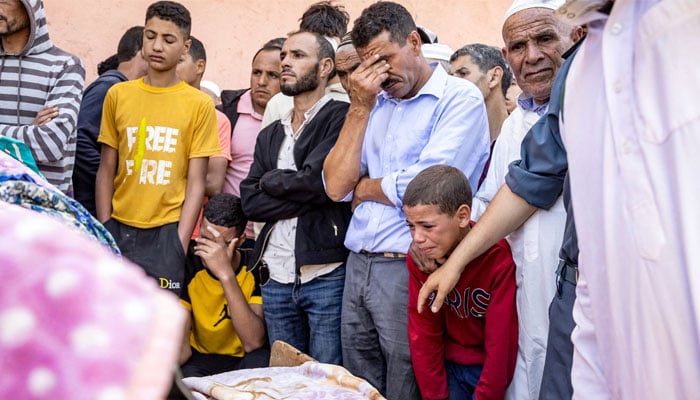 People mourn in front of the body of a victim killed in an earthquake in Moulay Brahim, Al Haouz province, on September 9, 2023. — AFP