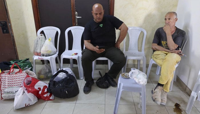 Palestinians from Gaza stranded in the Israeli-occupied West Bank, follow the news in a hotel room in Ramallah.AFP