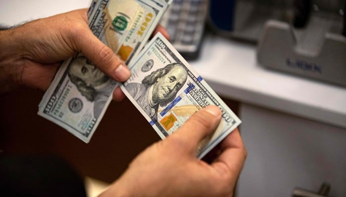 A currency exchange agent counts US Dollars at his company in Iraqs southern city of Basra, on December 8, 2023. — AFP