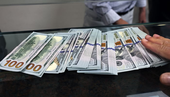 A teller shows US dollar bills at an exchange office in Ankara on July 20, 2023. — AFP