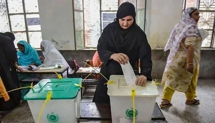 A woman casts her vote in Pakistans general election at a polling station during the general election in Lahore. — AFP/File