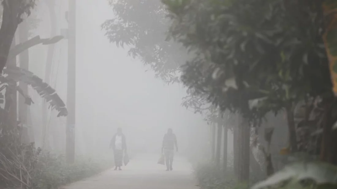 People walk on a road on a foggy winter morning in Louhajanj upazila of Munshiganj on Wednesday, January 3, 2023. Photo: Mehedi Hasan/Dhaka Tribune