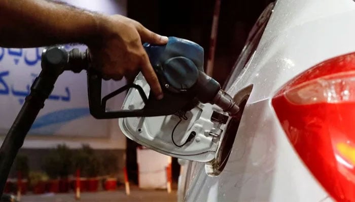 A worker holds a fuel nozzle to fill up a cars fuel tank at a petrol station in Karachi on September 16, 2023. — Reuters